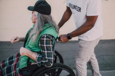 Volunteer pushing man in wheelchair