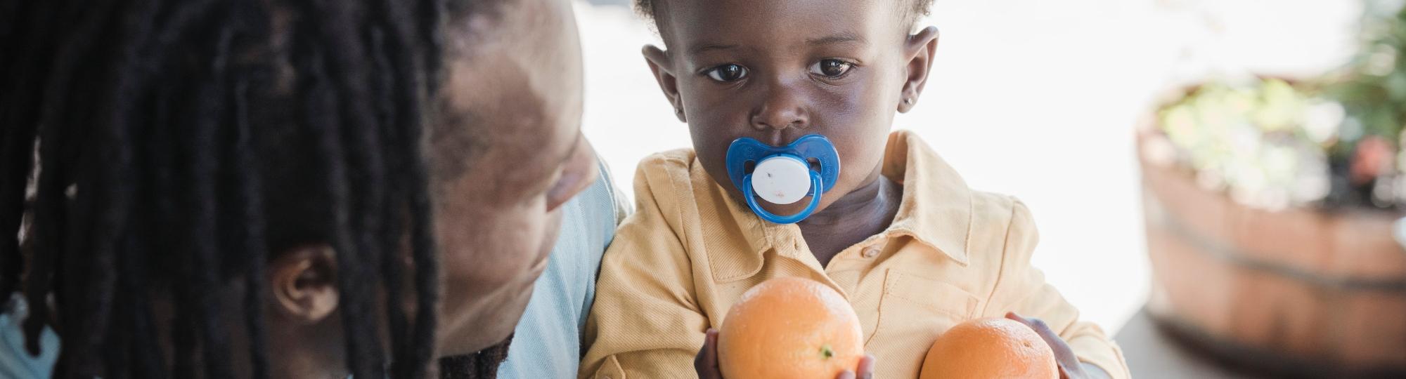 father holding baby with oranges